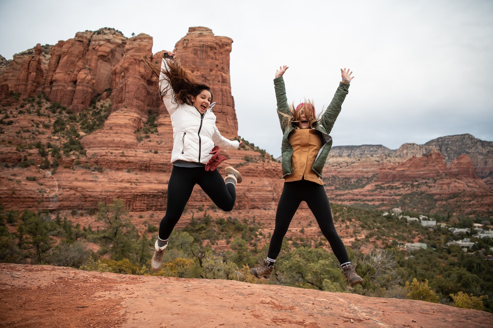 Friends jumping for joy against Sedona's red rock backdrop