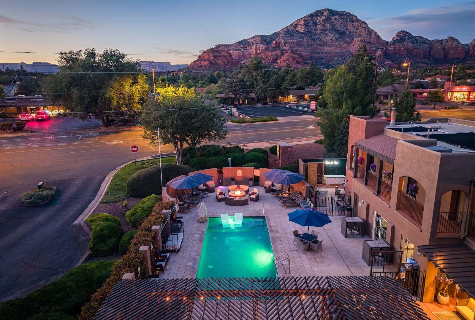 Aerial view of Arroyo Pinion Hotel's pool and patio at dusk with the Uptown Sedona street and red rock mountains in the background