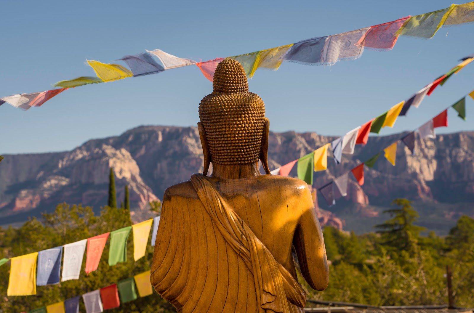 Buddha statue and prayer flags facing the red rocks in Sedona, a peaceful spot for meditation