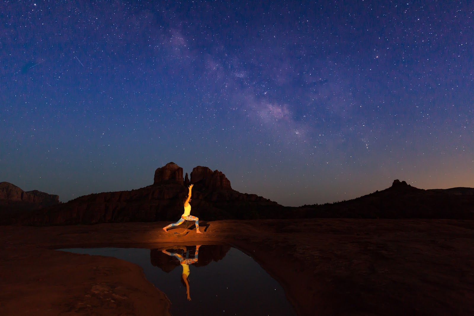 Yoga pose under the Milky Way with Cathedral Rock reflected in water in Sedona