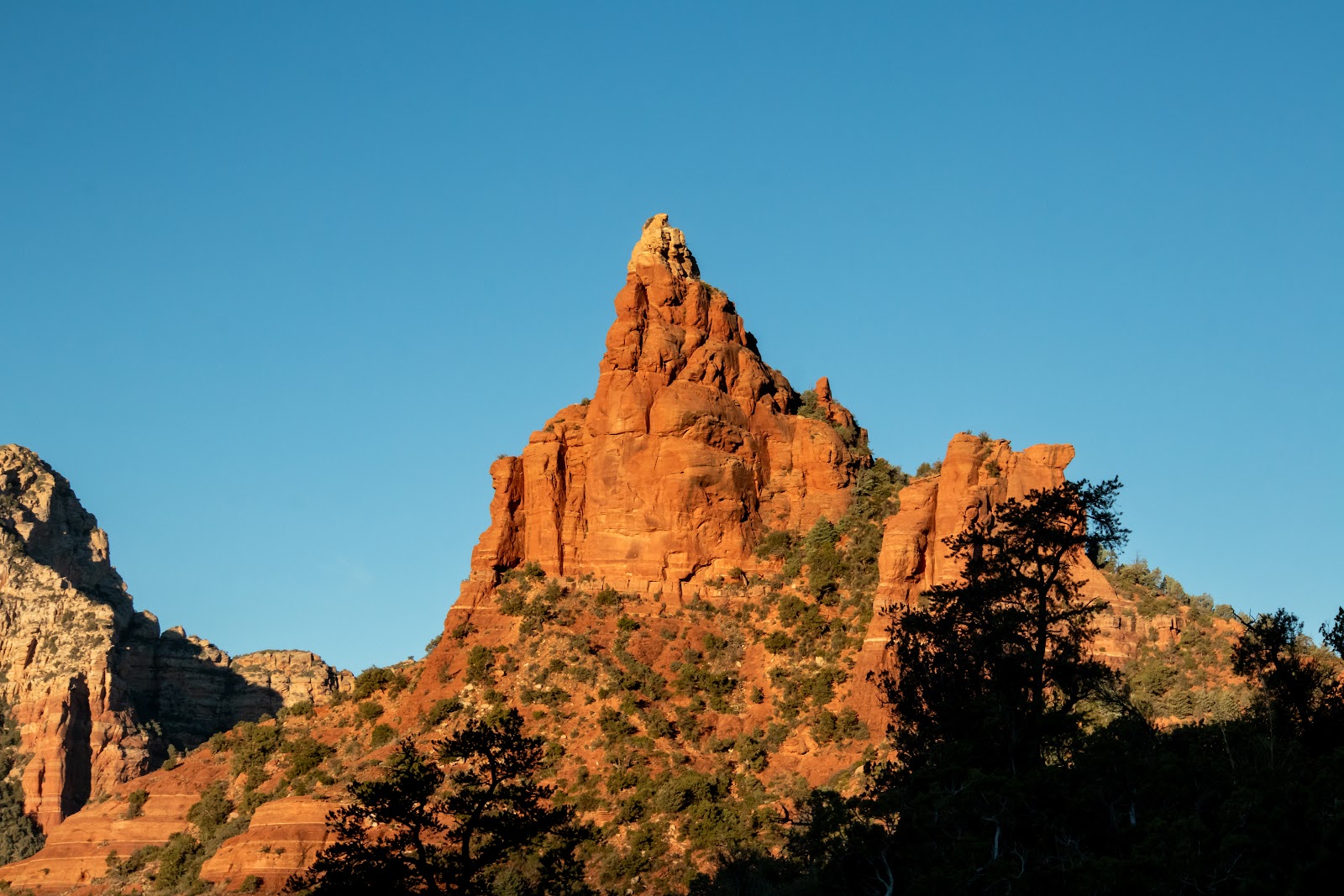 Sedona red rocks rising against a clear sky, showing the resistant cap rock and stair-step profile