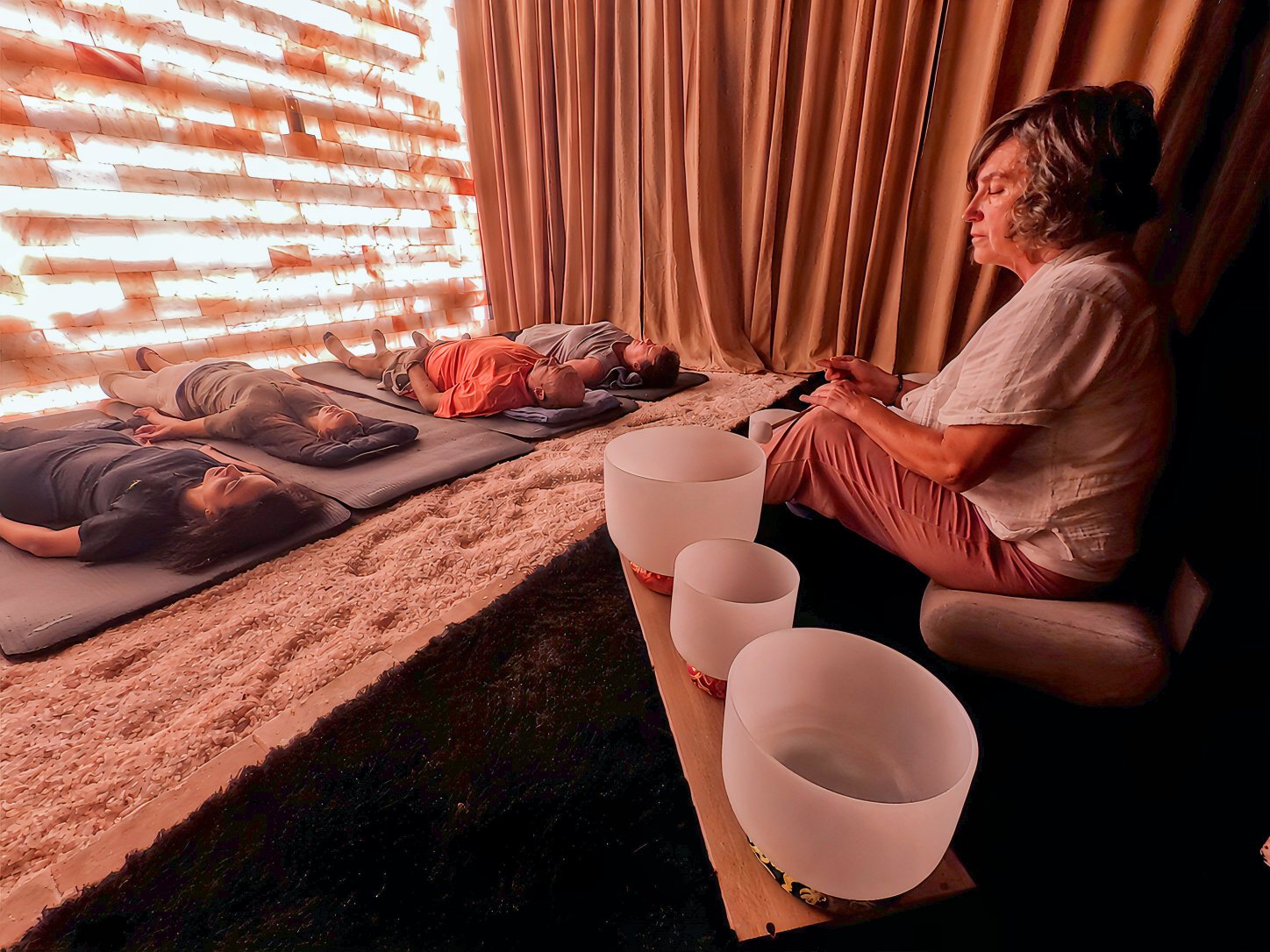 Guests lying on mats during a Sedona sound healing session while a practitioner plays crystal bowls